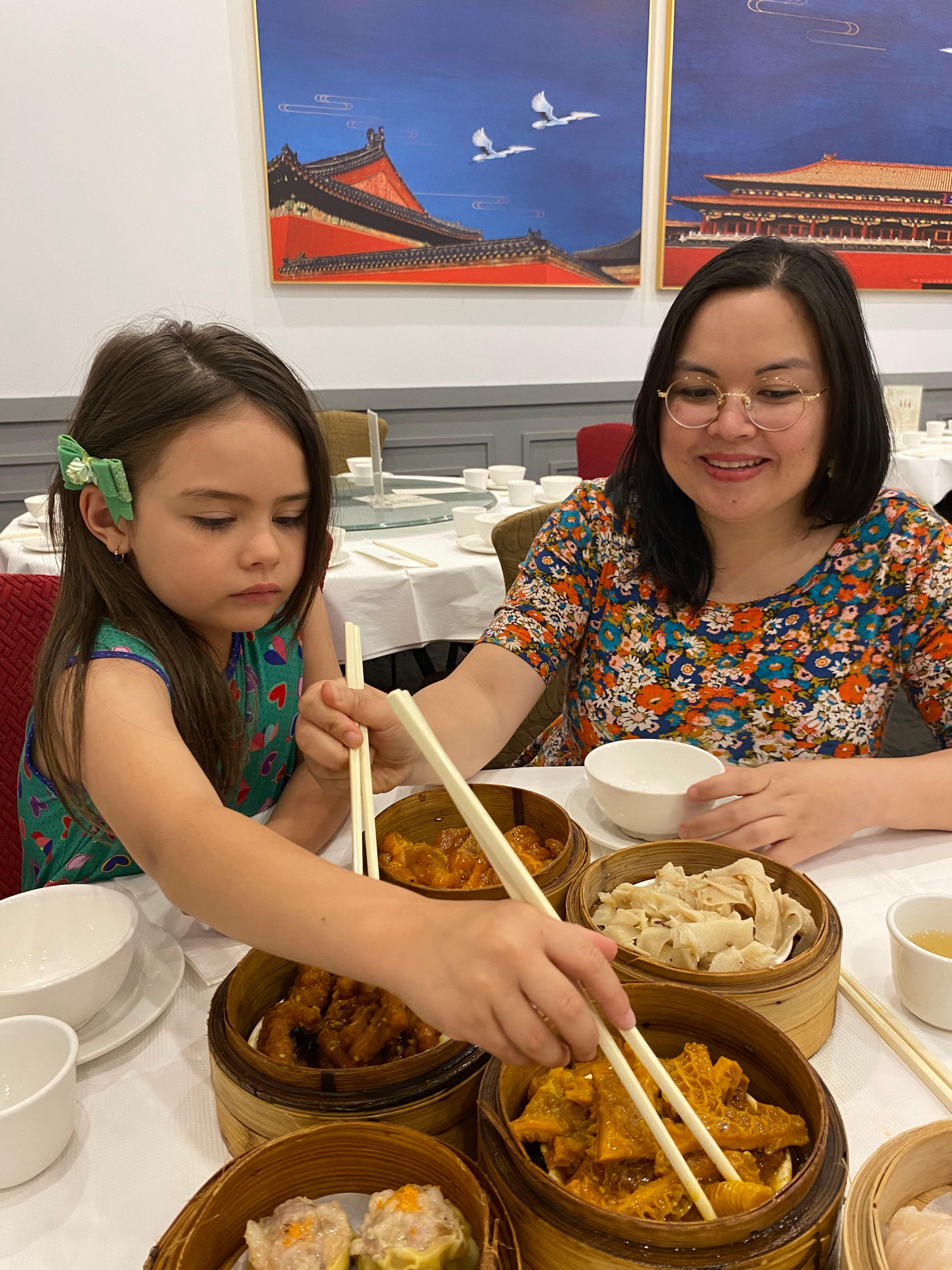 Sheila, a middle-aged Australian woman with a Vietnamese background, shares chicken feet with her young daughter at yum cha. 