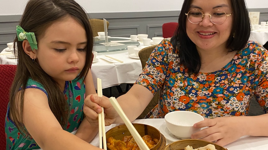 Sheila, a middle-aged Australian woman with a Vietnamese background, shares chicken feet with her young daughter at yum cha. 