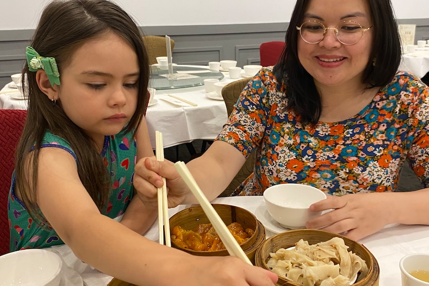 Sheila, a middle-aged Australian woman with a Vietnamese background, shares chicken feet with her young daughter at yum cha. 