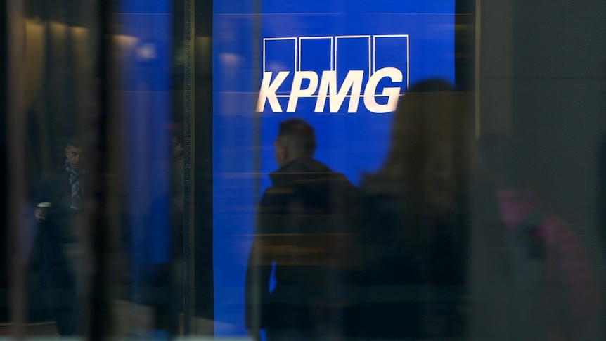 People silhouetted against a white and blue KPMG logo. 