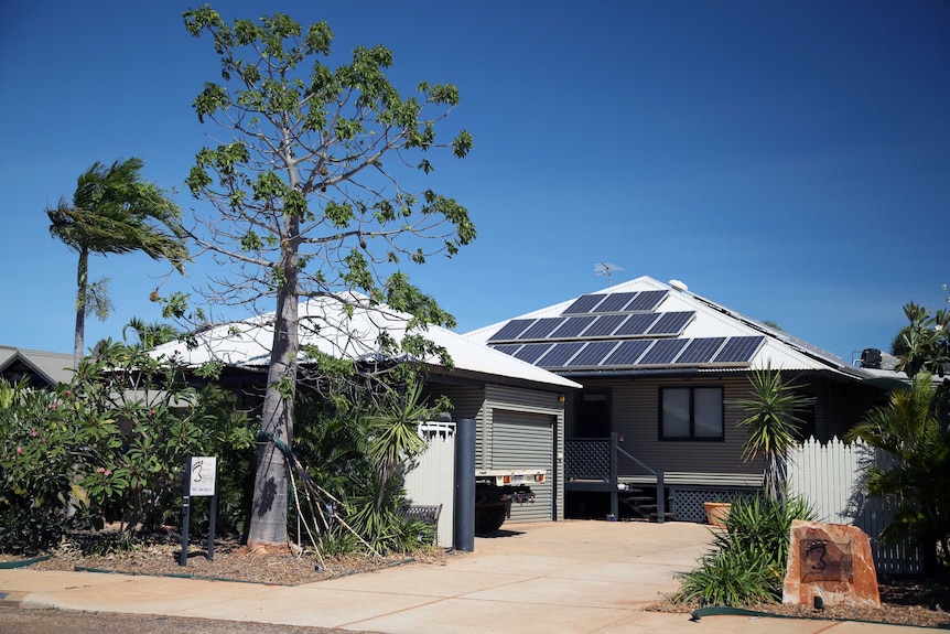 A house in the sunshine with solar panels on the roof.