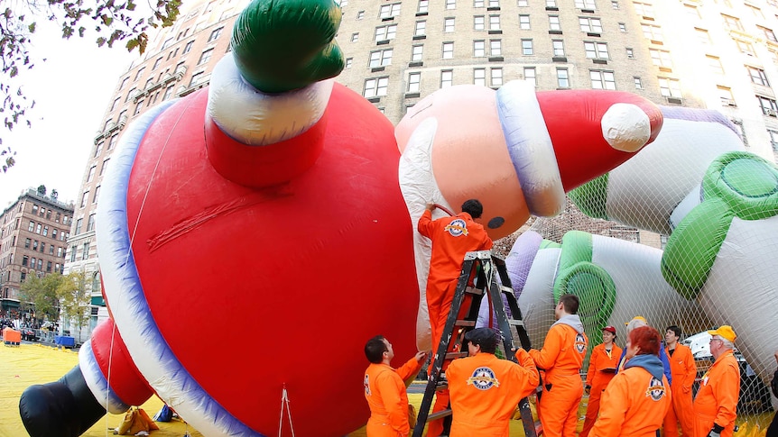 Workers fill a balloon in the shape of Santa Claus