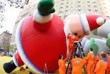 Workers fill a balloon in the shape of Santa Claus