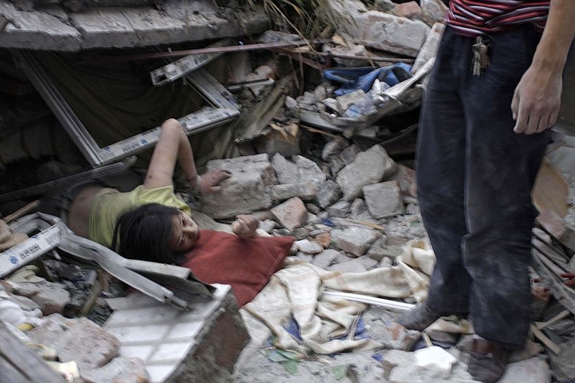 A survivor tries to escape from the debris of a collapsed building