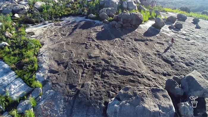 Aerial photo with figure walking along large rock escarpment