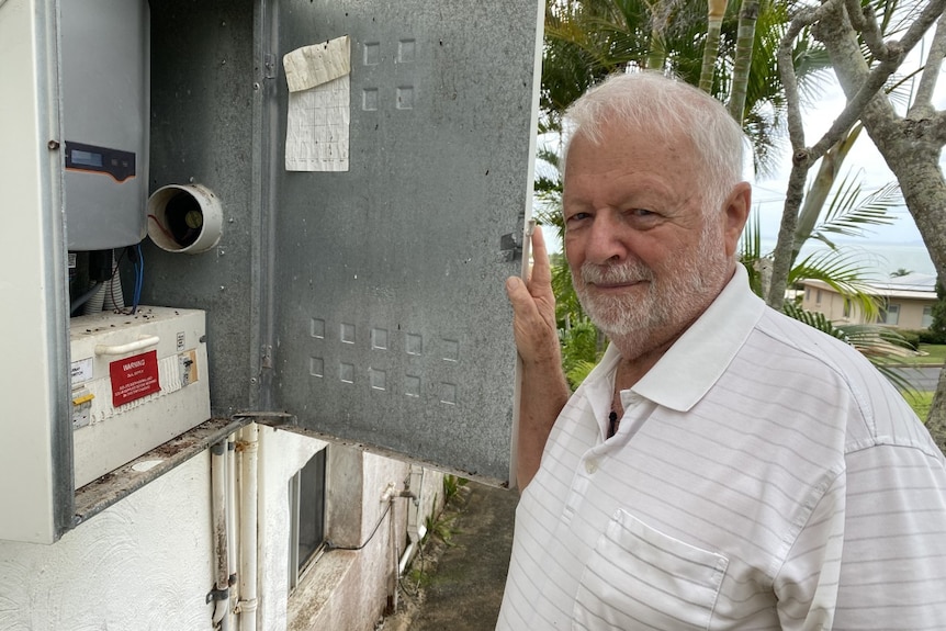 A man stands in front of his power box at his house