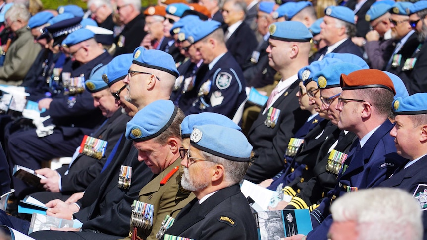 Men wearing blue berets in a crowd.