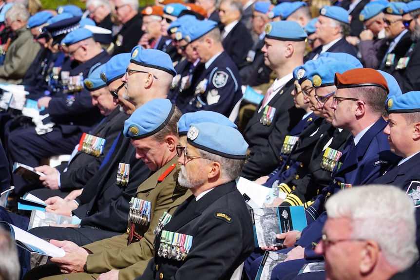 Men wearing blue berets in a crowd.