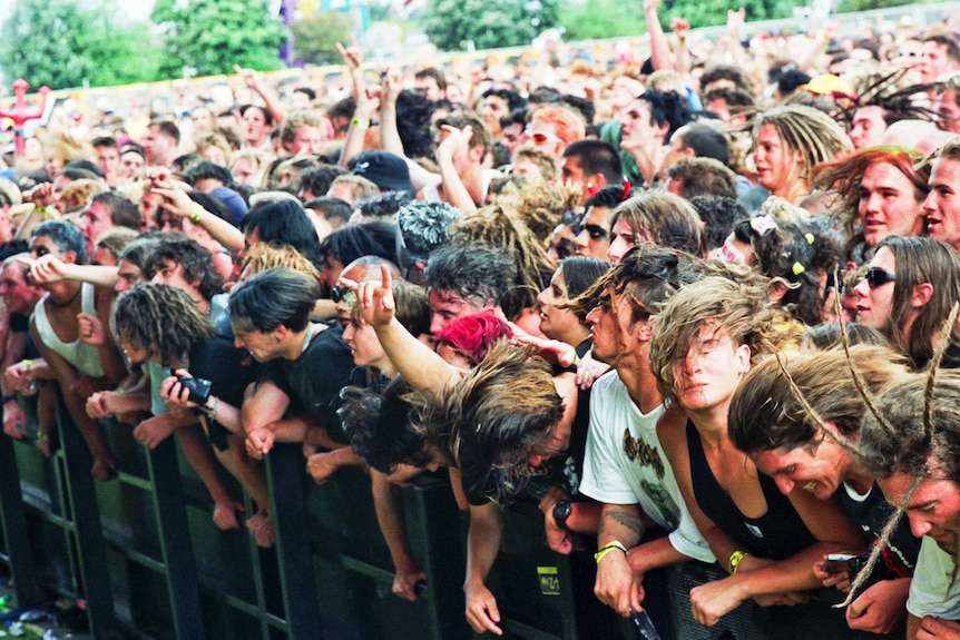 Crowd members squished up against a barrier, many throwing their long hair around