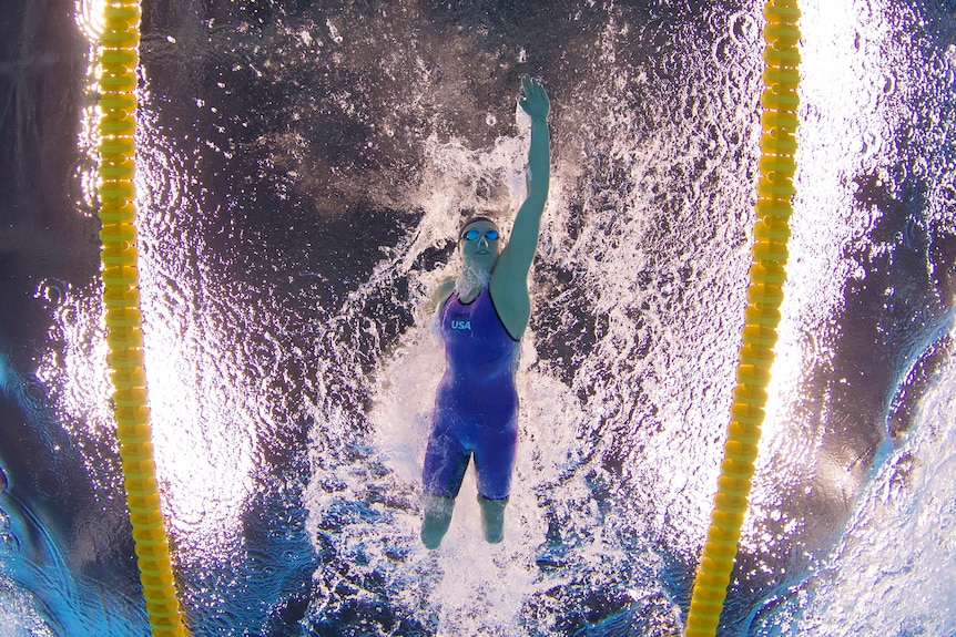 A view from underneath as a female Paralympic swimmer surges through the water .