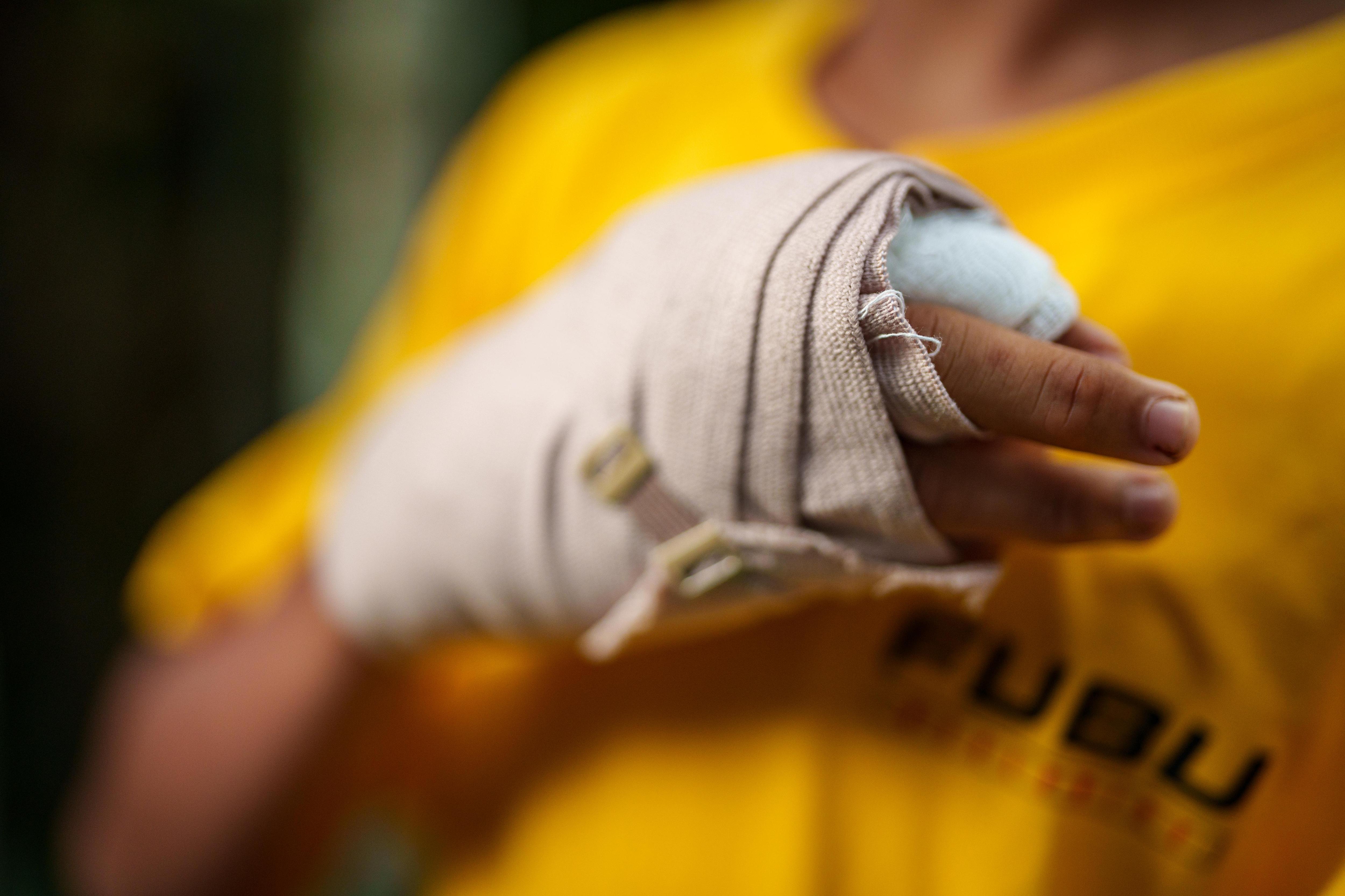 A young Filipino boy's right hand is wrapped up in a bandage. His yellow tshirt is visible in the background.