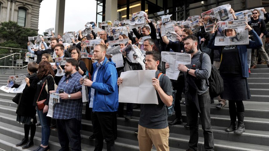 Staff at The Age newspaper hold up copies of the paper as they protest Fairfax Media job cuts.