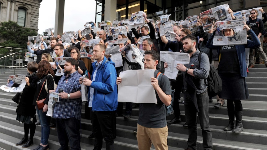 Staff at The Age newspaper hold up copies of the paper as they protest Fairfax Media job cuts.