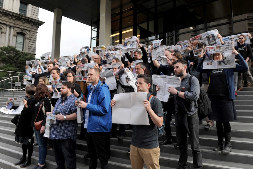 Staff at The Age newspaper hold up copies of the paper as they protest Fairfax Media job cuts.