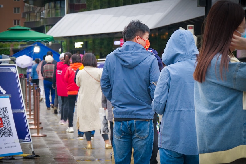 A line of people in Beijing, all wearing masks 