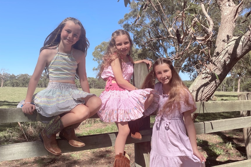 Alison Russell's daughters Imogen, Yvette and Madeleine sit on a fence