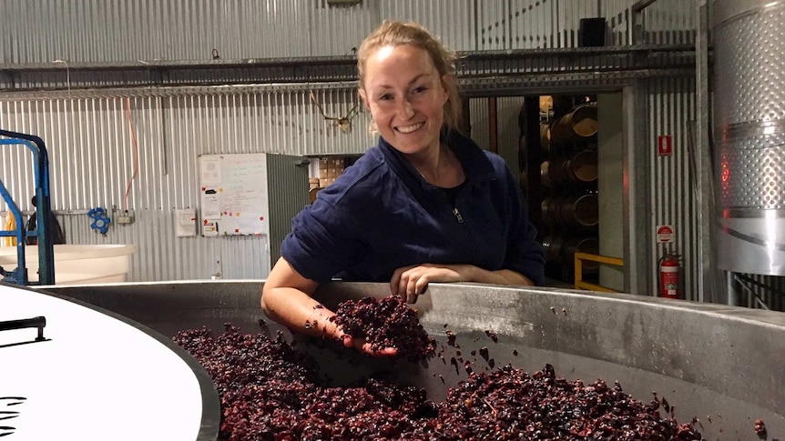 Winemaker Nadja Wallington standing with a handful of grapes at a winery in central west New South Wales