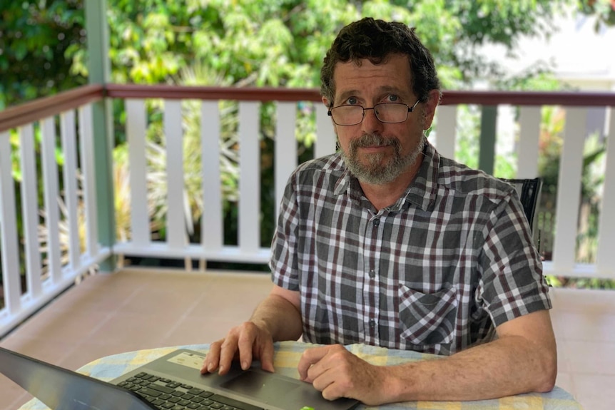 Professor Peter Ridd sitting at a table with a laptop in front of him.