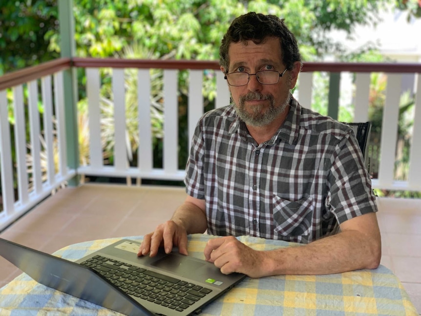 Professor Peter Ridd sitting at a table with a laptop in front of him.