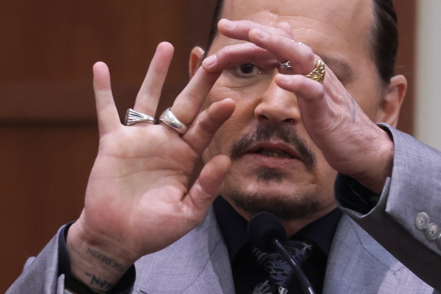 Johnny Depp displays the middle finger of his hand to show where he was injured.