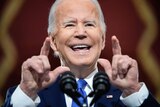 Close up of Joe Biden speaking at a podium and pointing with two fingers