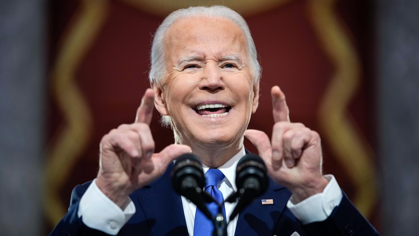 Close up of Joe Biden speaking at a podium and pointing with two fingers