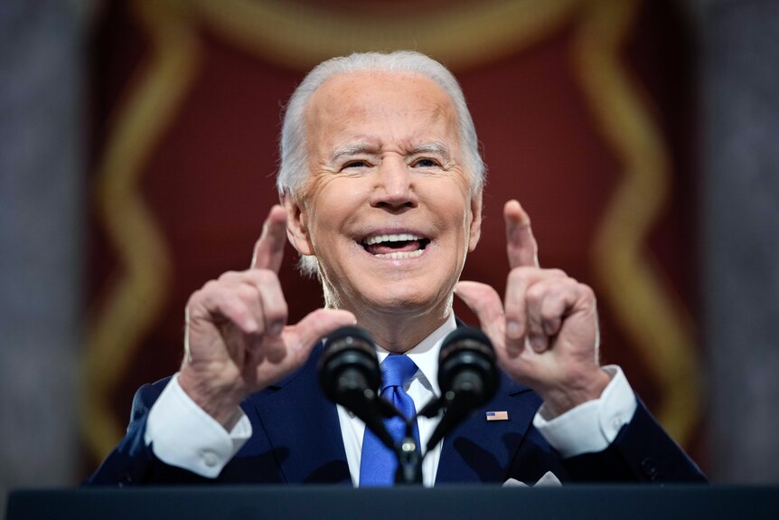 Close up of Joe Biden speaking at a podium and pointing with two fingers