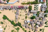 An aerial photo of a village which has been inundated with brown floodwaters.