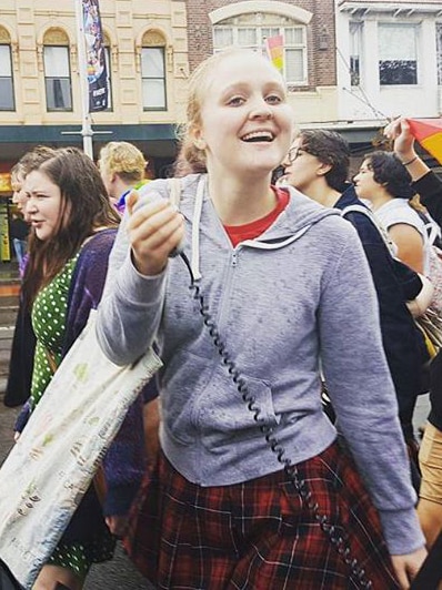 Young woman holding microphone amongst a protest.