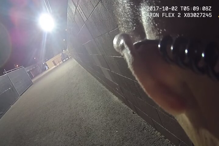 The back of a policeman's head is seen next to a brick wall looking in the direction of the Mandalay Bay hotel.