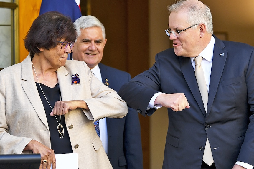 Pat Turner has her left elbow out, touching the elbow of Prime Minister Scott Morrison.