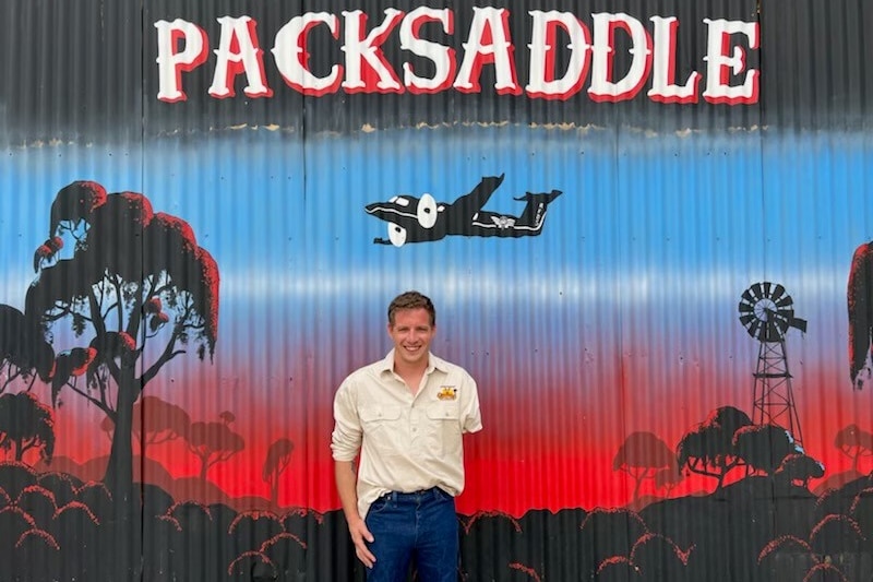 A man with one arm stands in front of a mural.