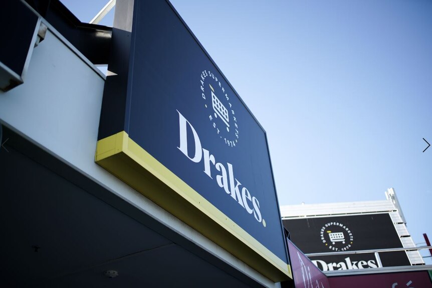 A black and yellow sign with the words "Drakes Supermarket" on it