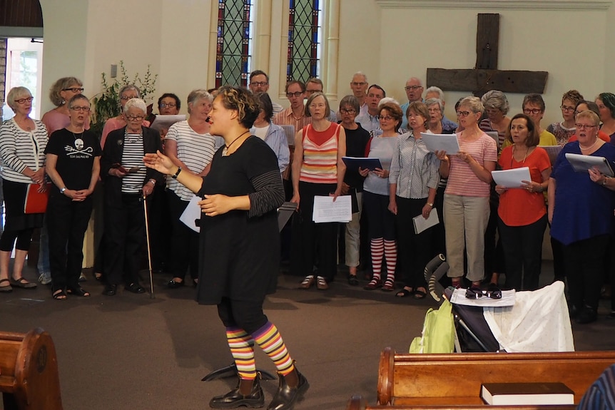 Nicky Johnson conducting a choir outside