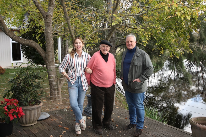 An elderly man and his adult son and daughter wide shot in art studio