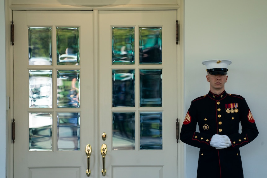 A Marine stands guard outside the doors of the West Wing of the White House