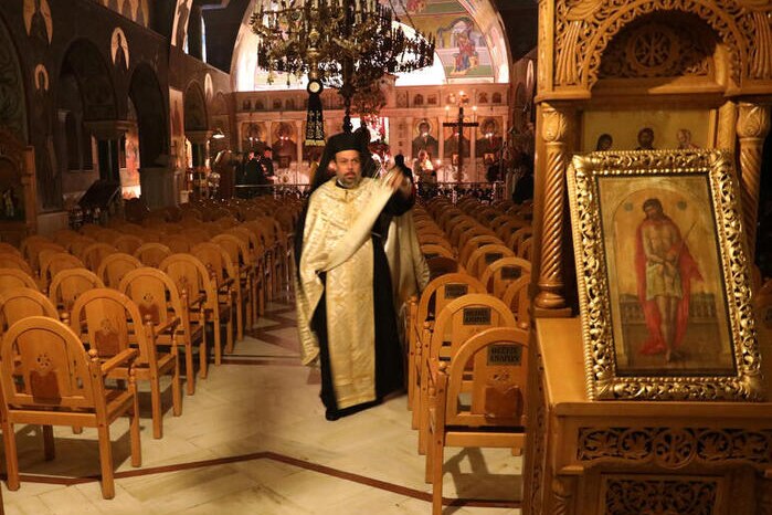 A Greek Orthodox priest in the aisle of an empty church.