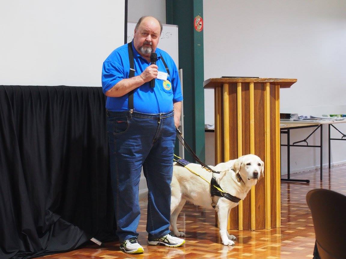Человек с микрофоном, стоящий рядом с собакой -гида
