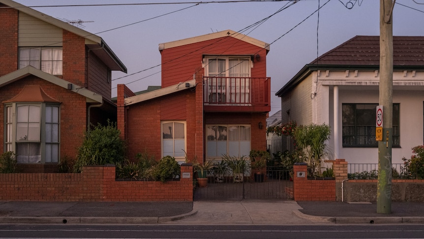 Three free-standing houses on a quiet suburban street at dusk.