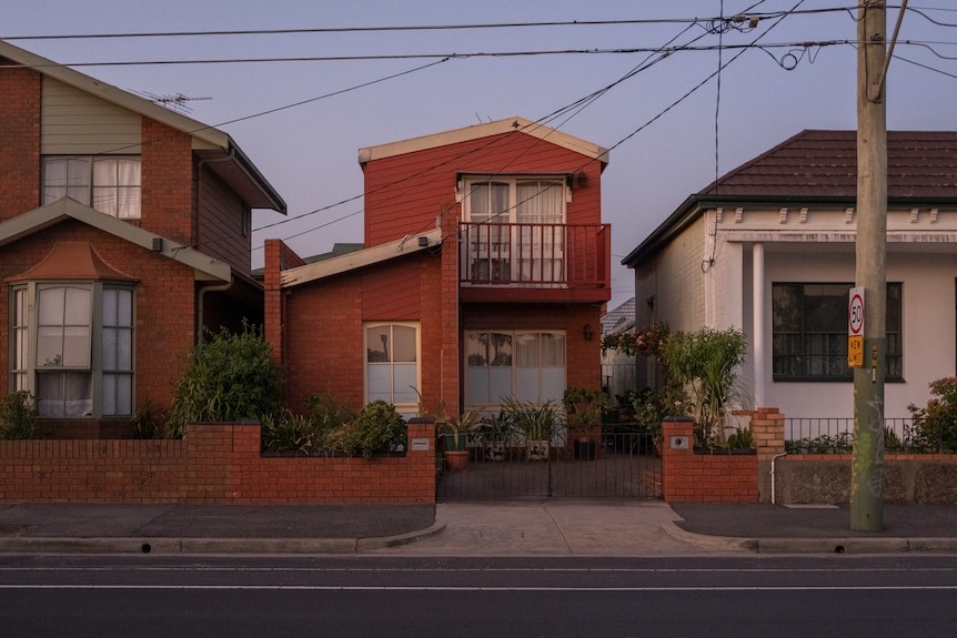 Three free-standing houses on a quiet suburban street at dusk.