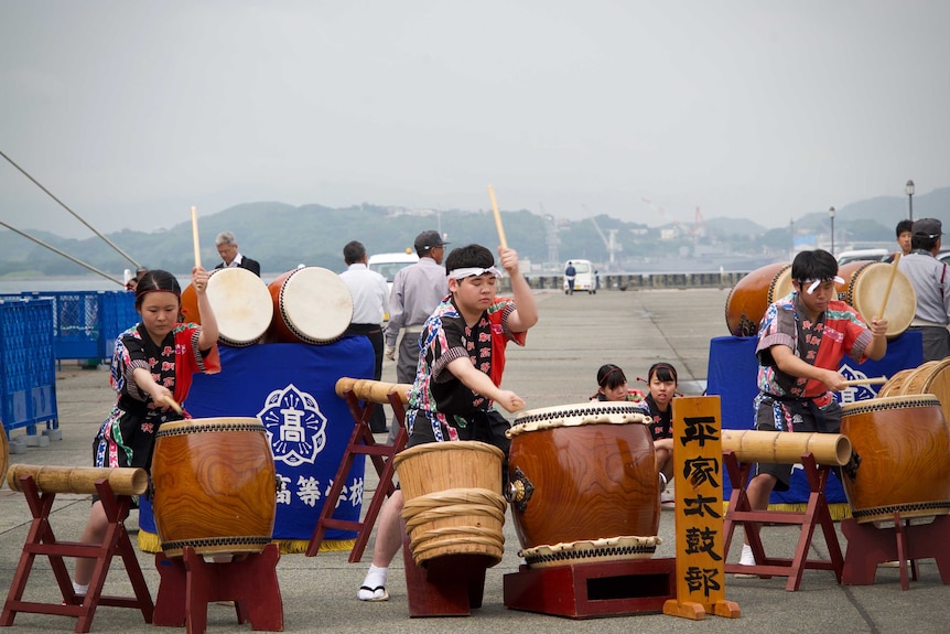 Teenagers drumming large Japanese traditional drums
