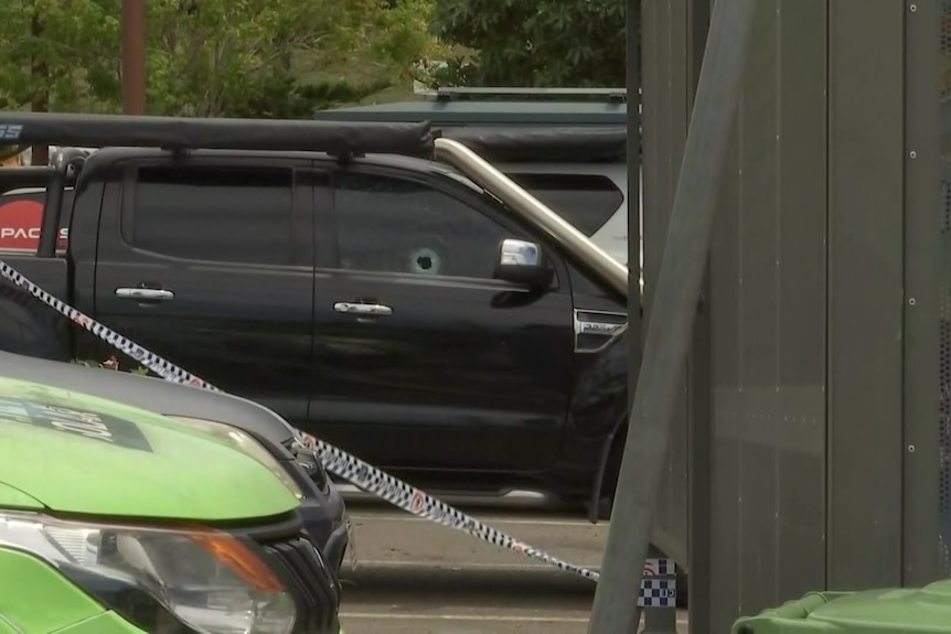 A black ute with a small bullet hole in the driver's window. 
