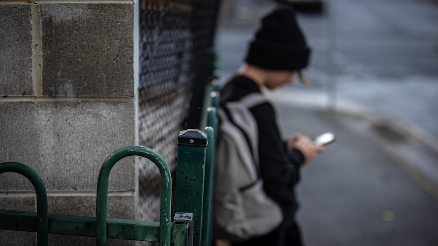A teenager in a beanie looking at a phone