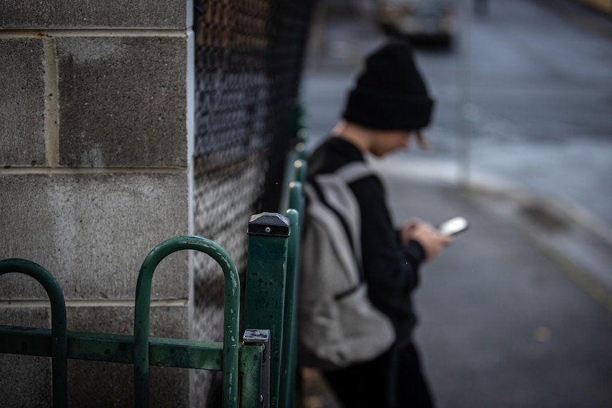 A teenager in a beanie looking at a phone