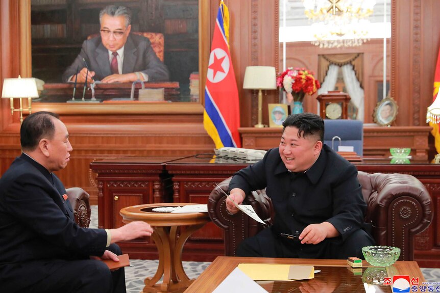 Kim Jong-un, right, meets envoy Kim Yong-chol, left, as Kim Jong passes him a signed piece of paper in an ornate office.
