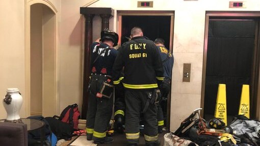 New York City firefighters look down at the elevator shaft.