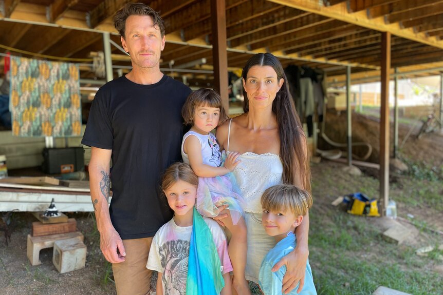 a family posing underneath their house