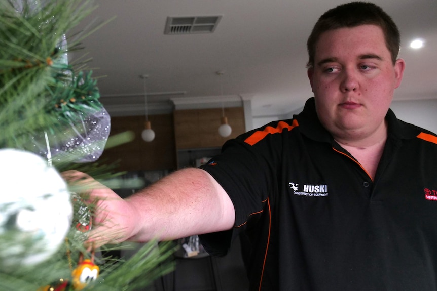 A man reaches out to a Christmas tree decoration