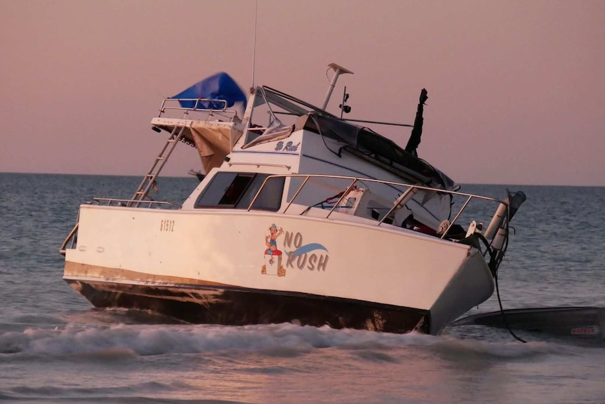 Image of a damaged boat sitting in low water off the coast of Cable Beach.