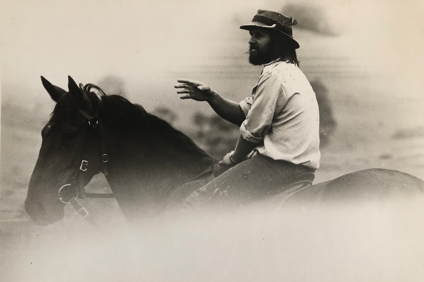 Old black and white photo of Roland in his youth with a beard riding a horse.